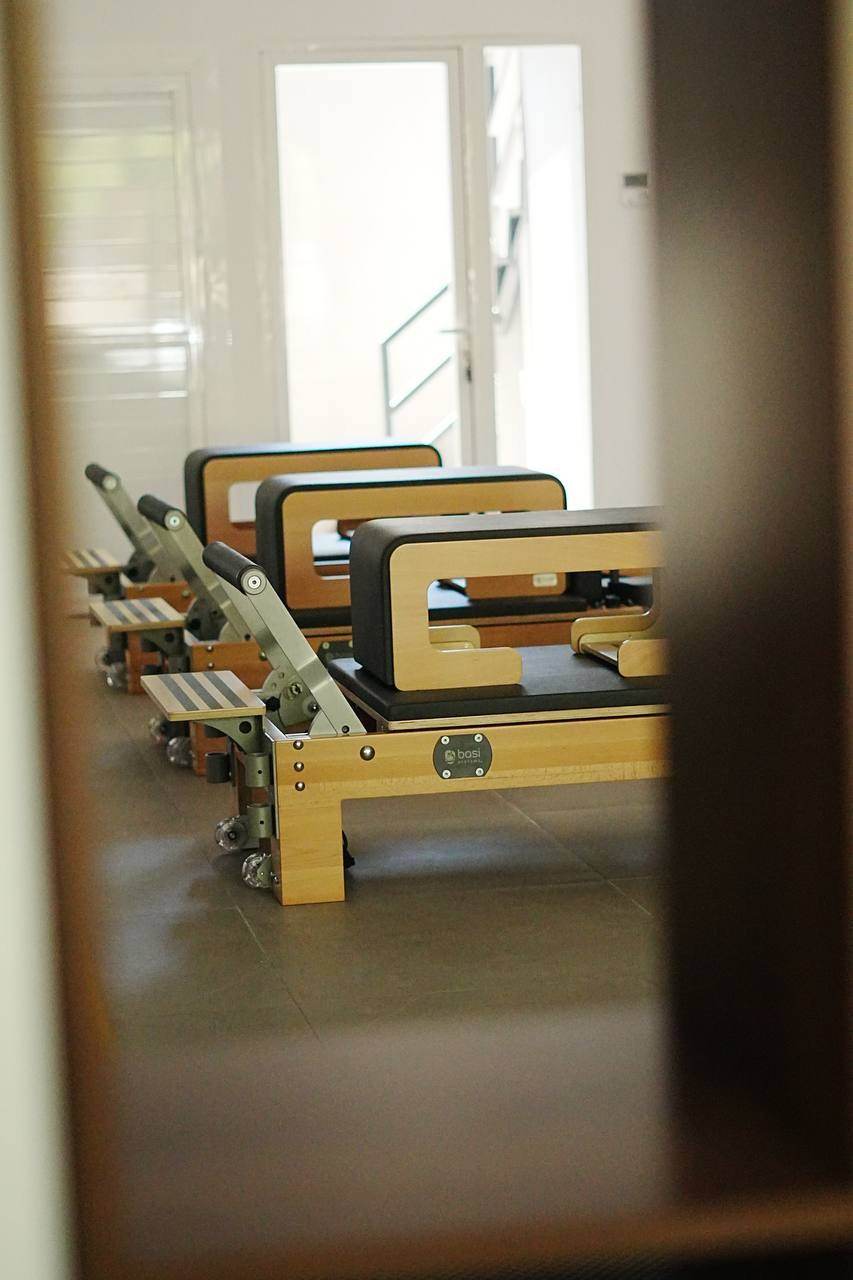 A row of BASI Systems Reformers with sitting boxes, seen between two wooden panels