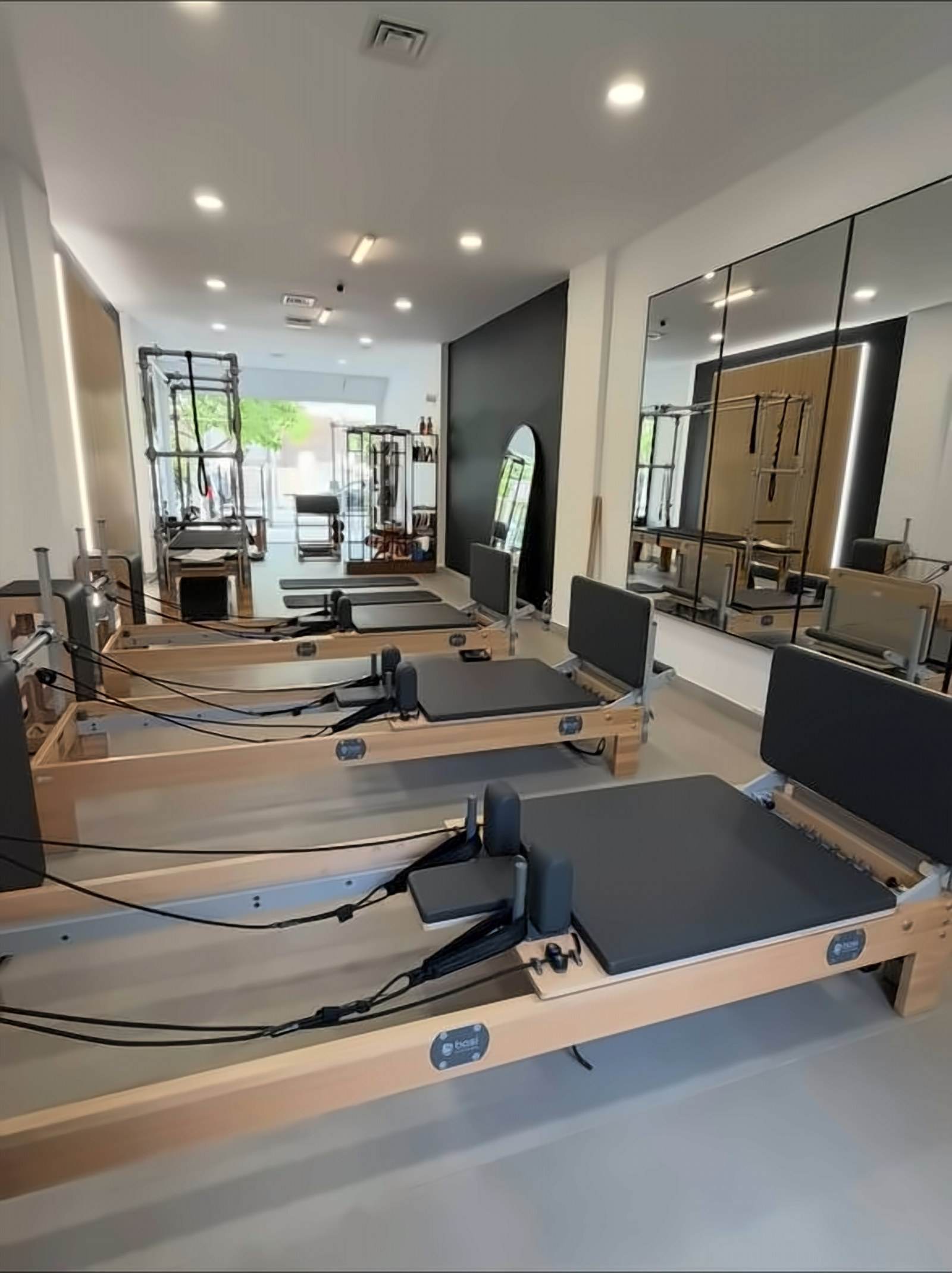 View down the length of the studio: reformers in a row, mirrors and daylight at the far end